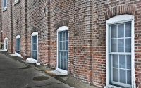five white windows that line the red brick wall along a street