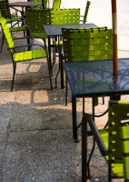 some green chairs on the pavement: outdoor seating area with some green chairs and a tables