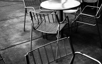 chairs and tables in black and white: metal chairs and tables on the pavement in black and white. street scene