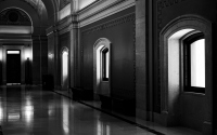 a door and three windows: a dark corridor lit by three windows leading to a closed door