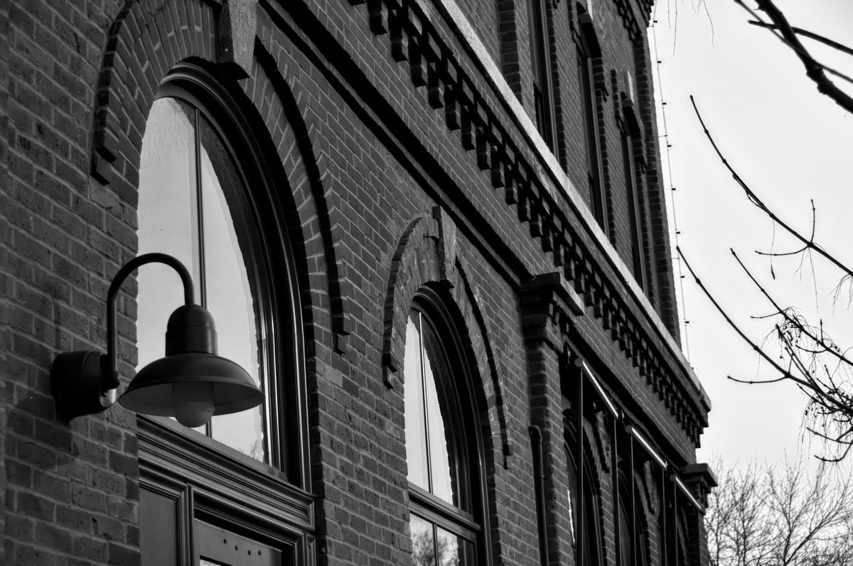 side of a brick building with arch windows in black and white